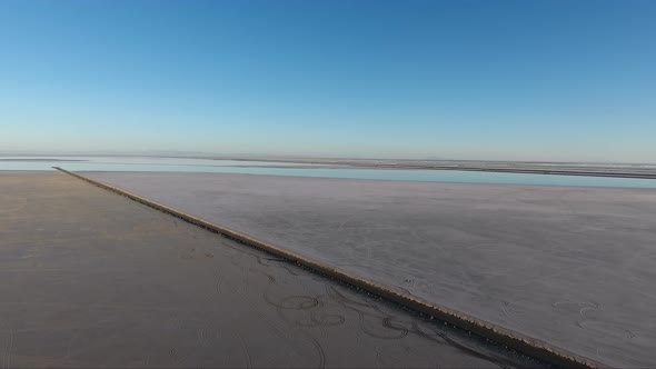 A drone shot flying over the Bonneville Salt Flats shows the Salt Flats causeway and distant highway