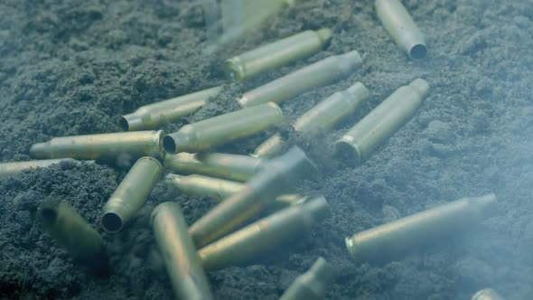 Bullet Cases Hit The Ground With Muzzle Flashes And Smoke