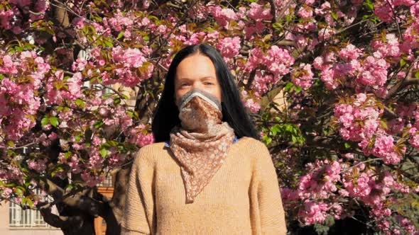 Adult Caucasian Woman in Mask on the Background Flowering Bushes
