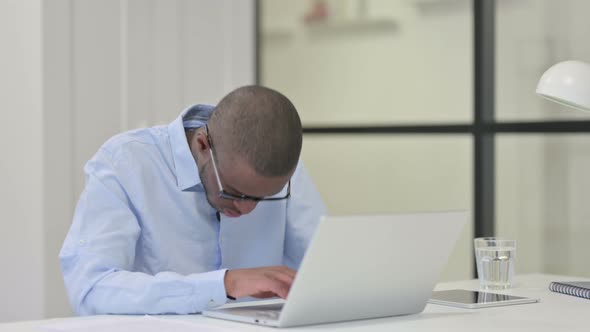 Tired African Man Sleeping While Working Laptop