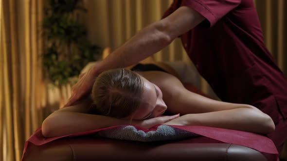 Spa Treatments Professional Masseur Makes a Relaxing Back Massage to a Young Female Beautiful Female