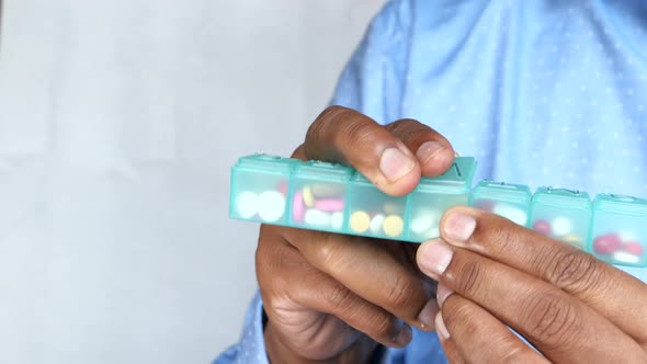 Young Man Taking Pill From Pill Box 