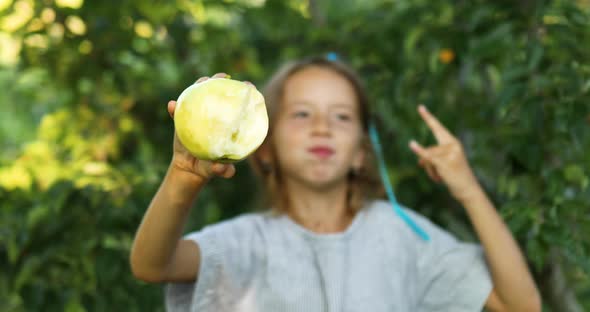 Cute little girl eat green apple in home garden outdoor, happy child