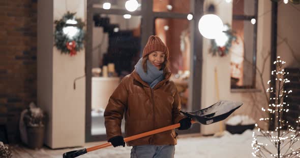 Portrait of Enthusiastic Woman with a Snow Shovel Outdoors