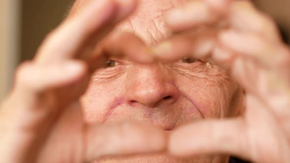 Elderly man congratulates on Valentine's Day. Portrait of Caucasian male 70 years old making heart s