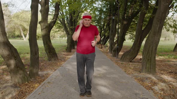 Senior Man Person Running on the Spot in Park. Mature Runner Man Training Workout, Listening Music
