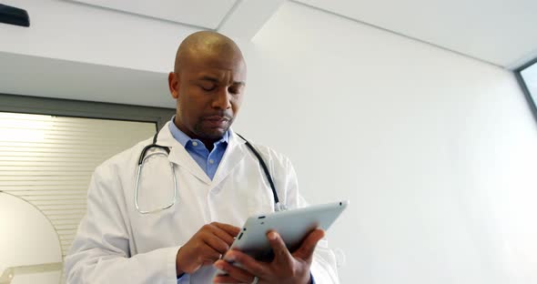 Doctor using digital tablet while walking in the corridor