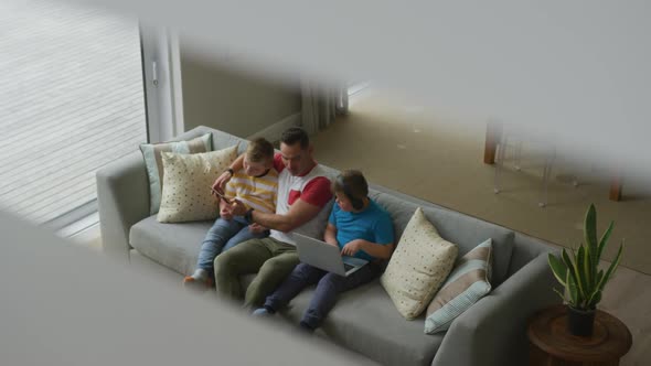 Caucasian father with two sons sitting in living room and using laptop