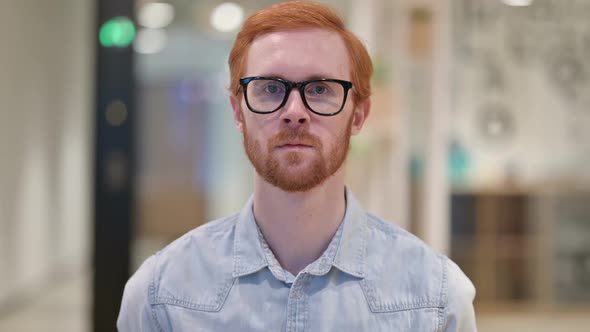 Serious Young Redhead Man Looking at Camera