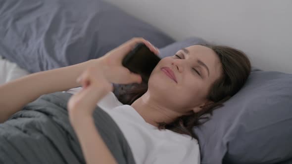 Woman Talking on Smartphone While Sleeping in Bed