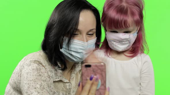 Mother, Daughter Wearing Medical Mask Holding Smart Phone Talking on Video Call