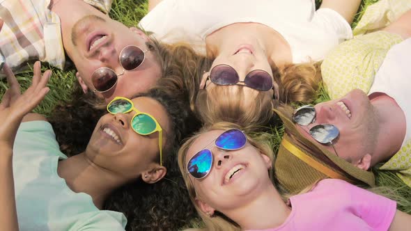 Happy Friends in Sunglasses Lying Grass, Talking and Laughing, Sharing Secrets