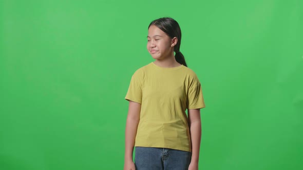 Young Asian Kid Girl Emotionally Flipping Something While Standing In The Green Screen Studio