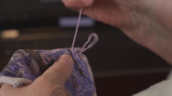 The Hands of an Elderly Woman Embroider a Cross