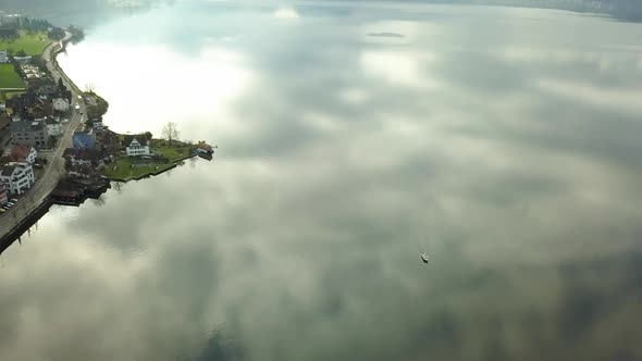 A boat is on a very reflective lake in Zug, Switzerland. The sun is setting.