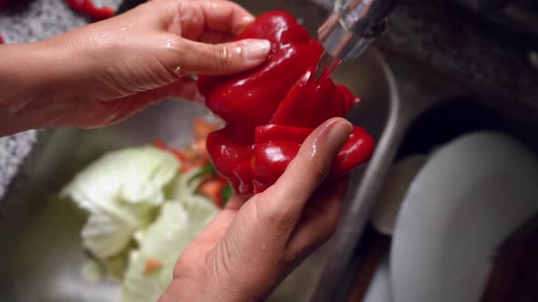 Hands Cleaning And Washing Cut Red Bell Pepper With Clean Running Water From Faucet. close up, slow