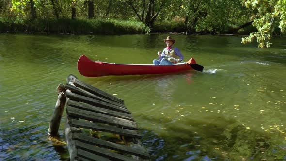 Cowboy in a Canoe Floats on the River in the Forest