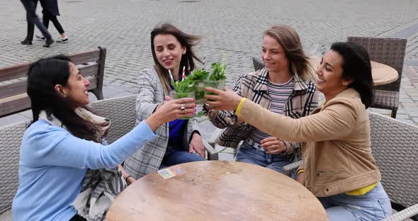 Attractive Young Women of Mixed Race Partying Outside in the City Drinking Cocktails and Smiling and