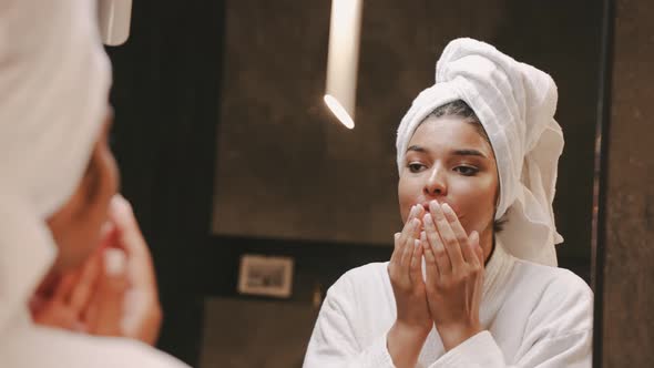 A Young Darkskinned Brunette in a Dressing Gown Uses a Patch for Lips Morning