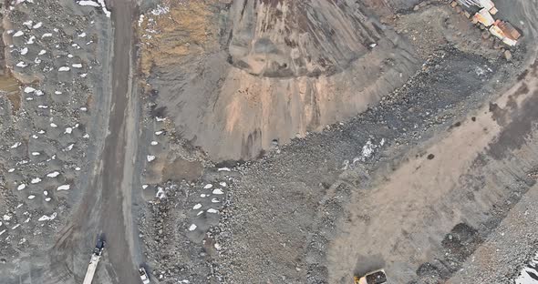 Heavy Mining Dump Trucks Driving Along the Opencast of Excavator Loads the Mined Rock in the Dump