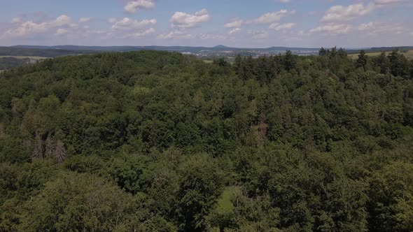Aerial footage of soft cumulus clouds over a lush green thicket of deciduous trees in the German cou