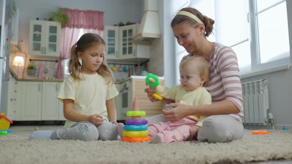 Woman Mother Plays With Two Children Girls Toys In The Room