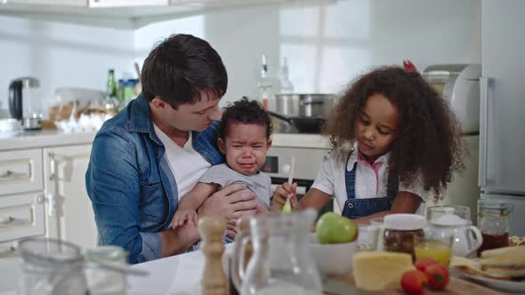 Crying Toddler with Family in Kitchen