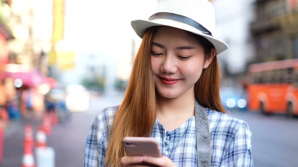 Smiling young Asian woman with shopping colour bags over mall background. using a smart phone