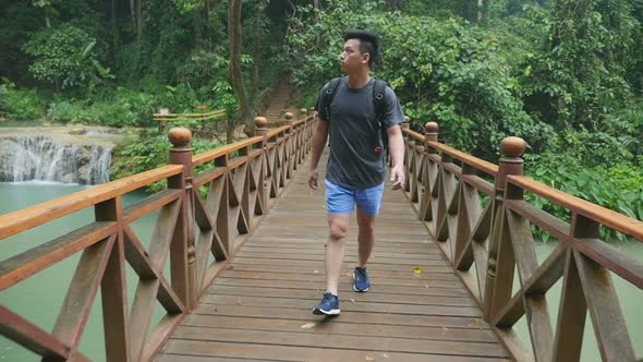 Hiker Walking On The Wooden Bridge Through River