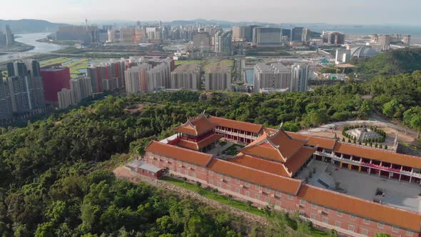 Rotating aerial view of A-Ma Temple with Macau cityscape in background