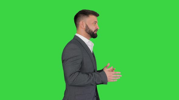 Serious Businessman Walking and Explaining Something on a Green Screen, Chroma Key.