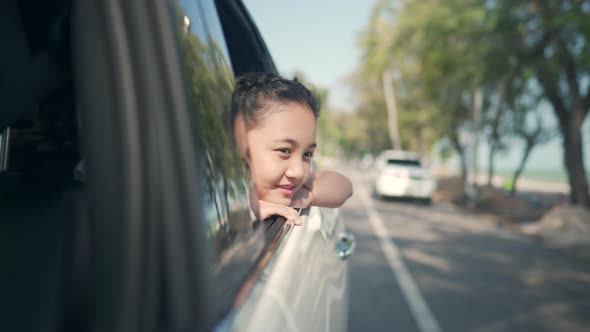 4K Asian girl kid in the car with pull her face and hand out of the window