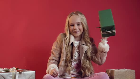 Smiling Teen Girl in Stylish Clothes Holding in Her Hand Green Box with Gift and Looking at Camera alt