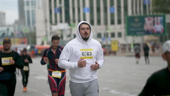 Chunky Body Shape Exhausted Sportsman Running with Group of Marathon Athletes