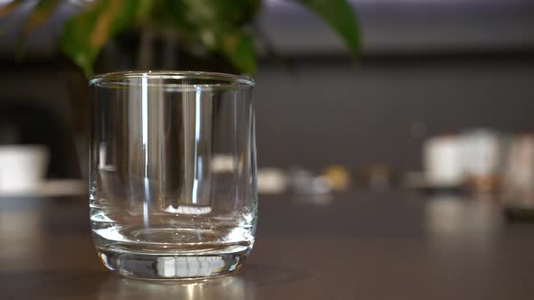 Fresh Orange Juice Pouring Into Glass Standing on Table Bar on Background