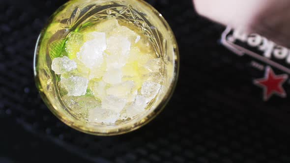 Man Adding Mint Leaves on a Night Cocktail on a Dark Background