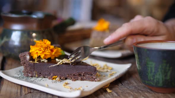 Plant Based Sugar Free Desserts. Close Up of Fork Taking a Piece of Raw Chocolate Cake Served on