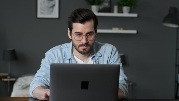 Young Man Freelancer Using Laptop, Typing, Scrolling, Surfing Web, Looking at the Screen