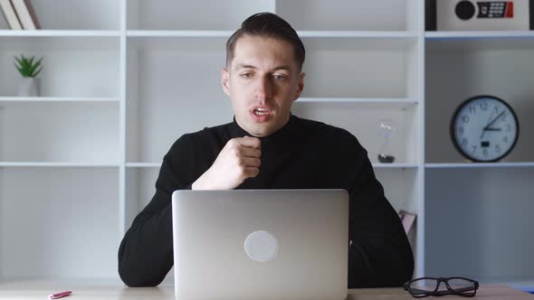 Smiling Businessman Using Laptop Computer for Video Conference While Sitting at Office