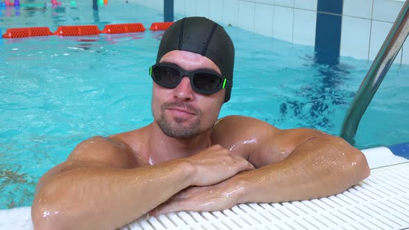 A Professional Swimmer Swims To the Edge of an Indoor Pool and Smiles at the Camera - Closeup