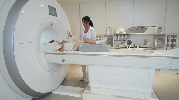 Magnetic Resonance Imaging Young Asian Woman Doctor Performs a Magnetic Tomographic Examination of a