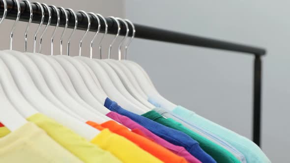 Various t-shirts arranged in a row on cloth rack 4k