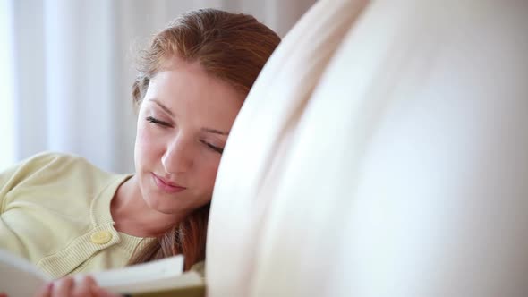 Young Woman Reading a Book on the Couch