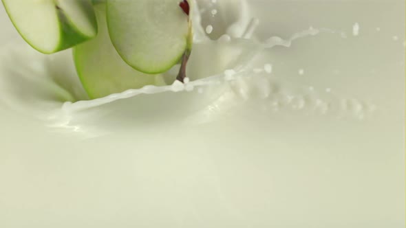 Super Slow Motion Pieces of Fresh Apple Fall Into the Milk with Splashes