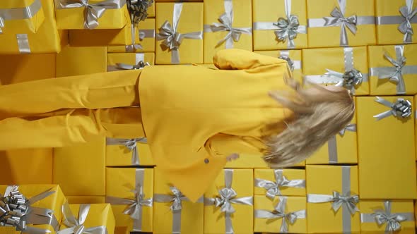 A Happy Blonde in a Yellow Suit and a Yellow Purse in Her Hands Poses in Front of the Camera Against