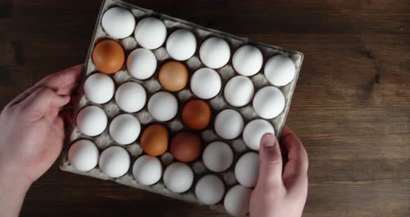 Men's Hands Put a Paper Stand with Raw Eggs on the Table. 