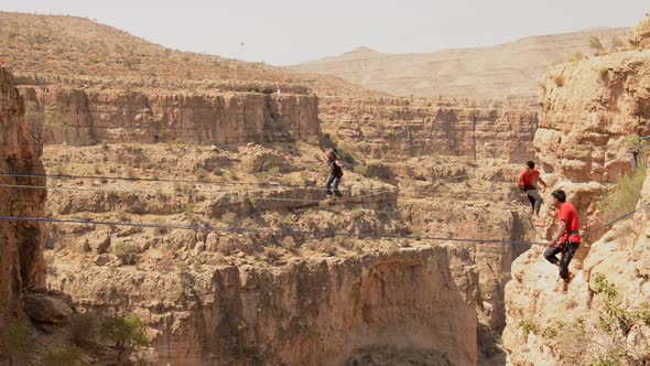 A man balances while tightrope walking and slacklining across a canyon