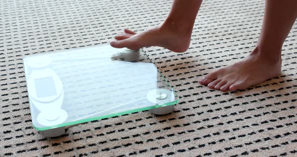 Female measuring weight on health scale