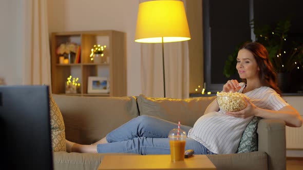 Pregnant Woman with Popcorn Watching Tv at Home