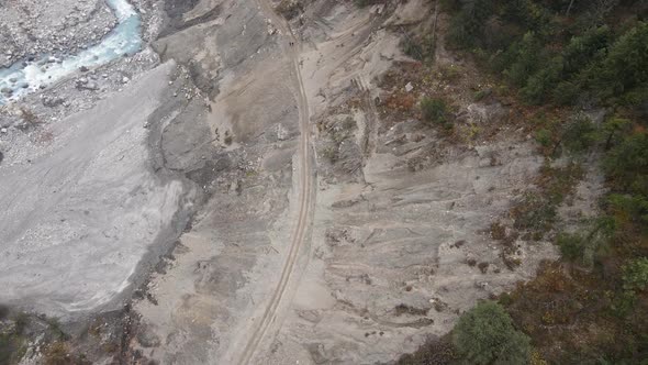 Aerial view flying down to landslide with dirt road and people walking